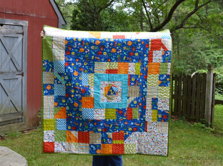A fun, oceany baby quilt, with improv borders and an icosahedron center, by Smiles Too Loudly